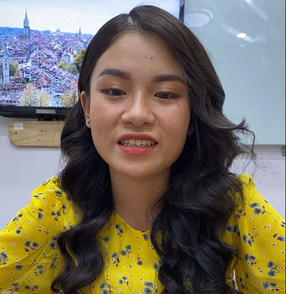 A young asian woman smiling in front of a tv.