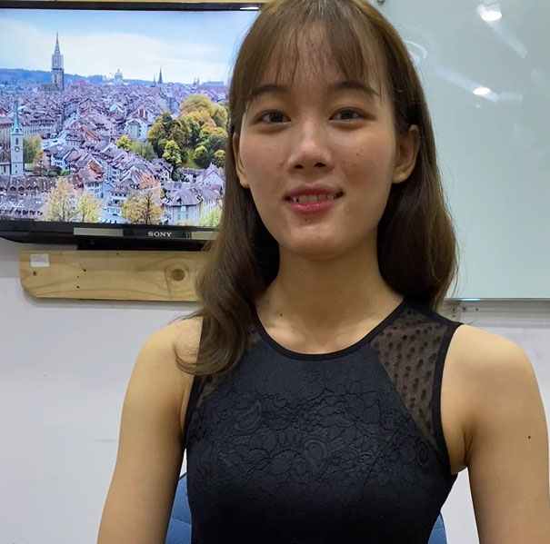A young Asian woman sitting in front of a TV.